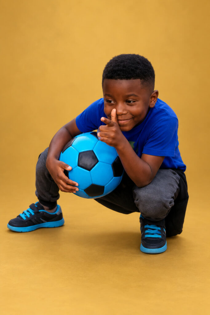 David Shelton as a young boy, crouching and smiling with a football