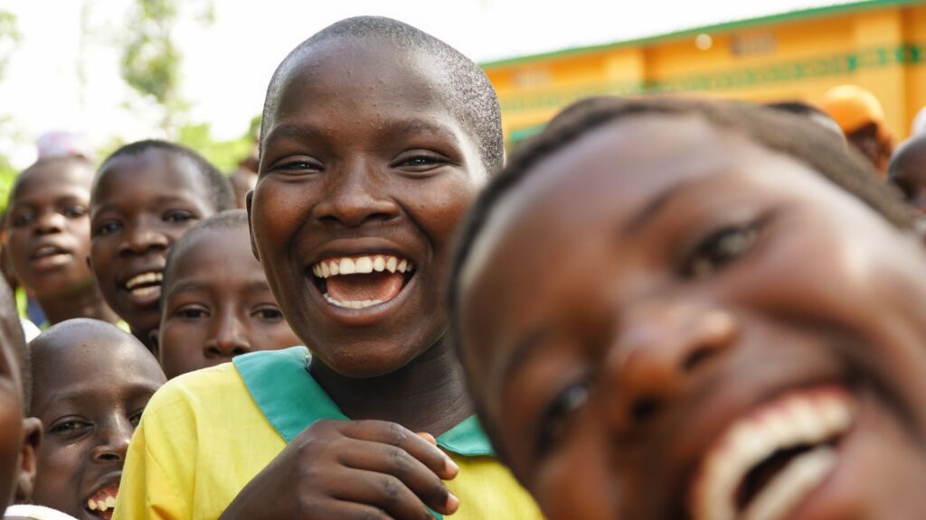 Children in school uniform laughing together in Uganda