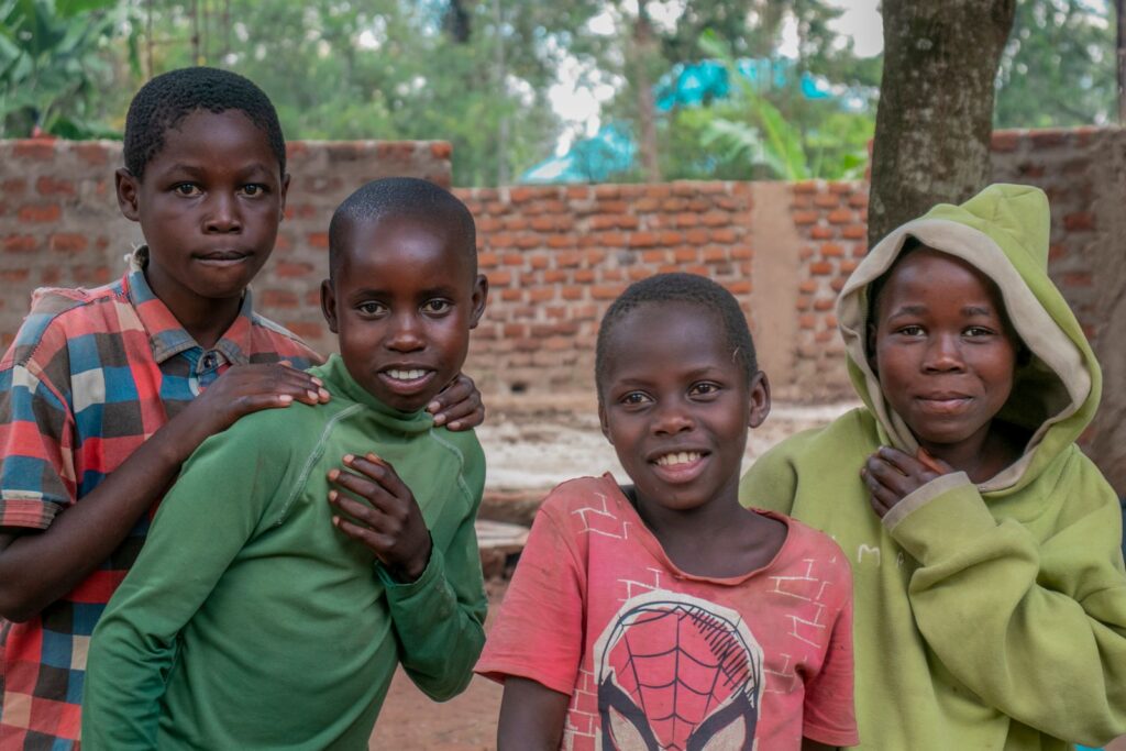 Four smiling children outdoors in rural Uganda